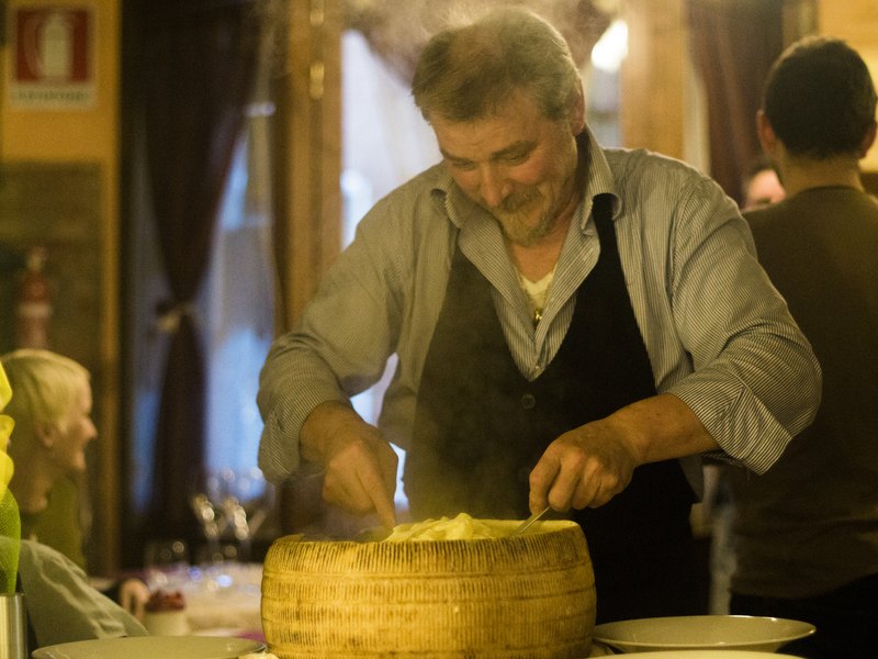 Ober schept pasta door een grote pecorino kaas.